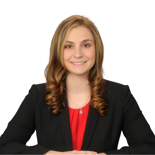 A woman with long wavy hair wearing a black blazer and red top is smiling and seated at a table.